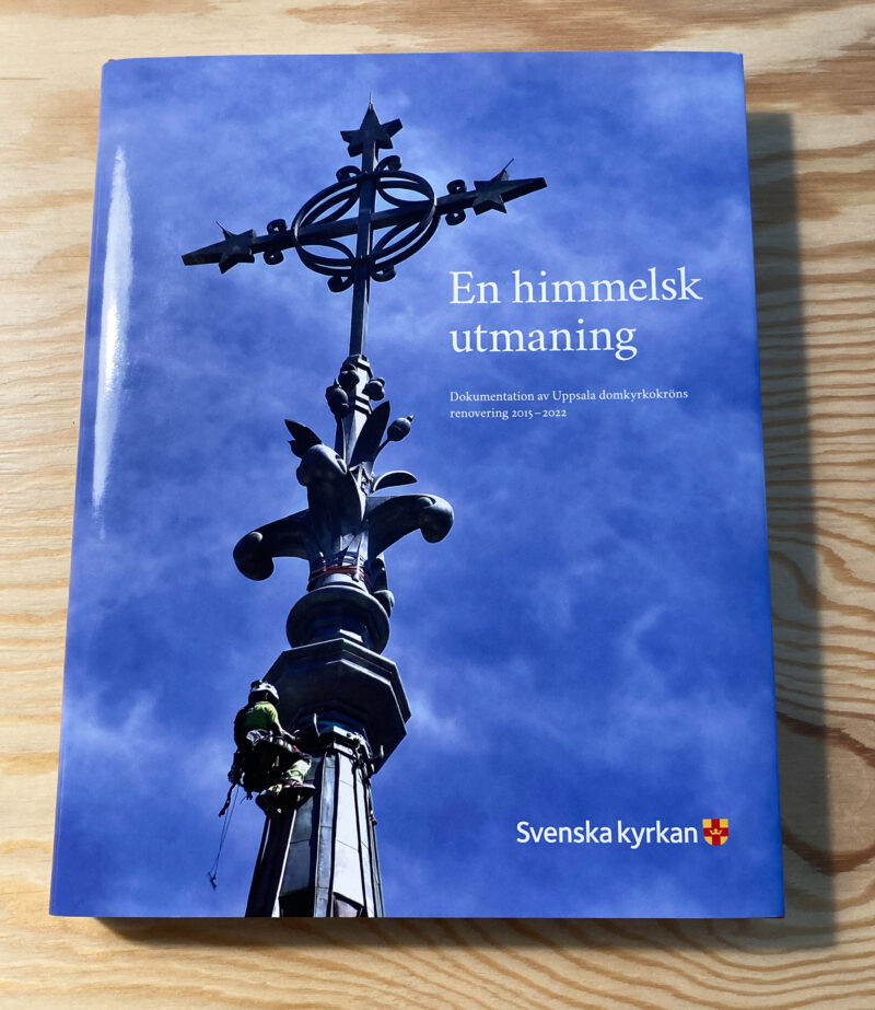 Bild på framsidan på en bok med titeln En himmelsk utmaning. Omslagsbilden föreställer Uppsala domkyrkas tornkrön och en klättrare som undersöker järndetaljer.